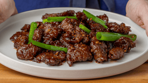 P.F. Chang's Mongolian Beef with dark sauce and green onions on a white plate