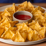 crab rangoons with sweet and sour dipping sauce on plate