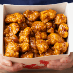 Chinese takeout orange chicken with glossy sauce served over steamed white rice