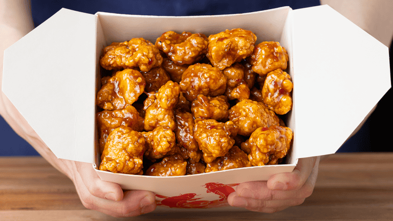 Chinese takeout orange chicken with glossy sauce served over steamed white rice