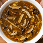 Chinese takeout hot and sour soup in a bowl with egg ribbons, wood ear mushrooms, and tofu