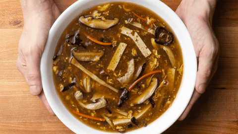 Chinese takeout hot and sour soup in a bowl with egg ribbons, wood ear mushrooms, and tofu