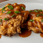egg foo young patties topped with brown gravy and sliced green onions