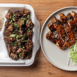 American teriyaki chicken served over white rice topped with sesame seeds and sliced scallions with japanese teriyaki on a white plate with shredded green cabbage