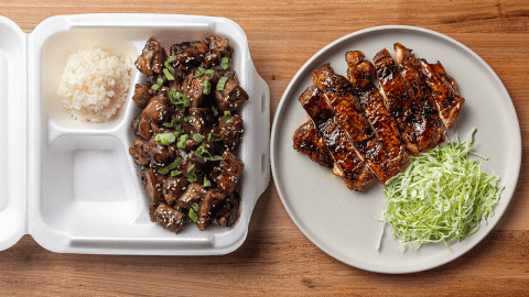 American teriyaki chicken served over white rice topped with sesame seeds and sliced scallions with japanese teriyaki on a white plate with shredded green cabbage