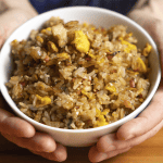 Benihana fried rice with sesame seeds and sliced green onion in a white bowl