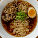 homemade ramen bowl with soy egg shredded pork and curly scallions
