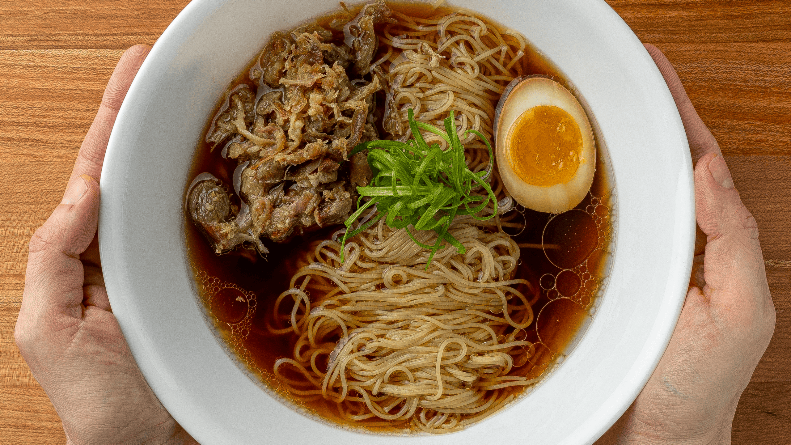 homemade ramen bowl with soy egg shredded pork and curly scallions