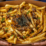 Japanese curry fries topped with bonito flakes sesame seeds scallions and kizami nori