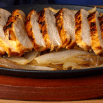 Tex-Mex chicken fajita taco with sliced chicken and caramelized onions on a comal