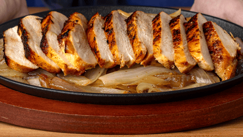 Tex-Mex chicken fajita taco with sliced chicken and caramelized onions on a comal