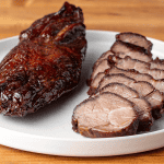 Sliced char siu Chinese BBQ pork with glossy maltose lacquer on a cutting board