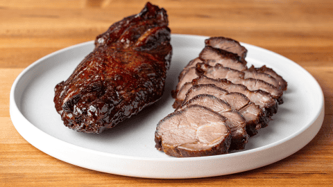 Sliced char siu Chinese BBQ pork with glossy maltose lacquer on a cutting board