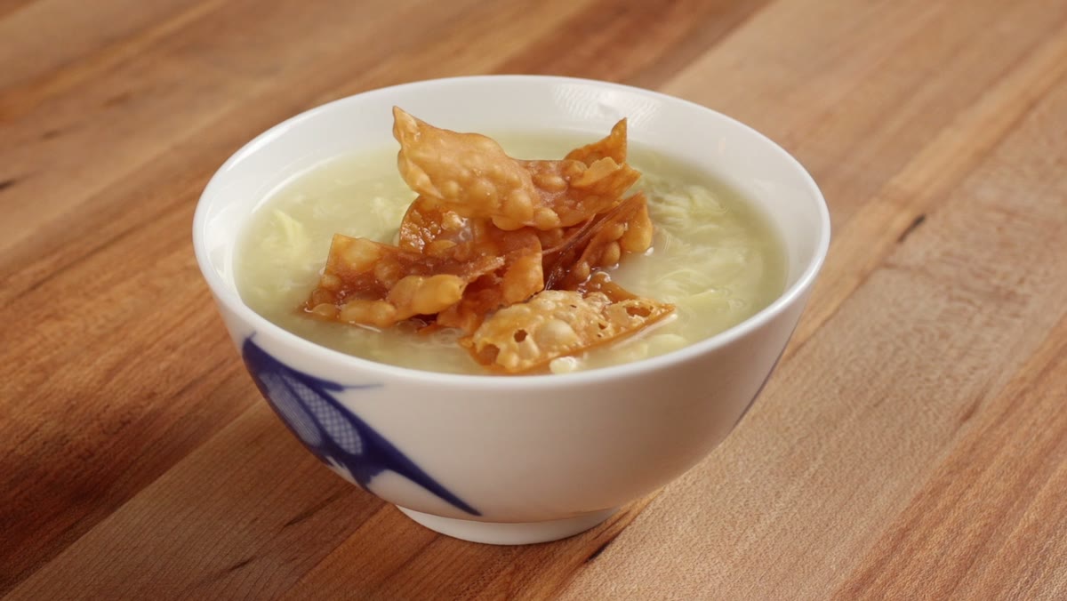 A bowl of egg drop soup topped with a pile of crispy fried wonton strips