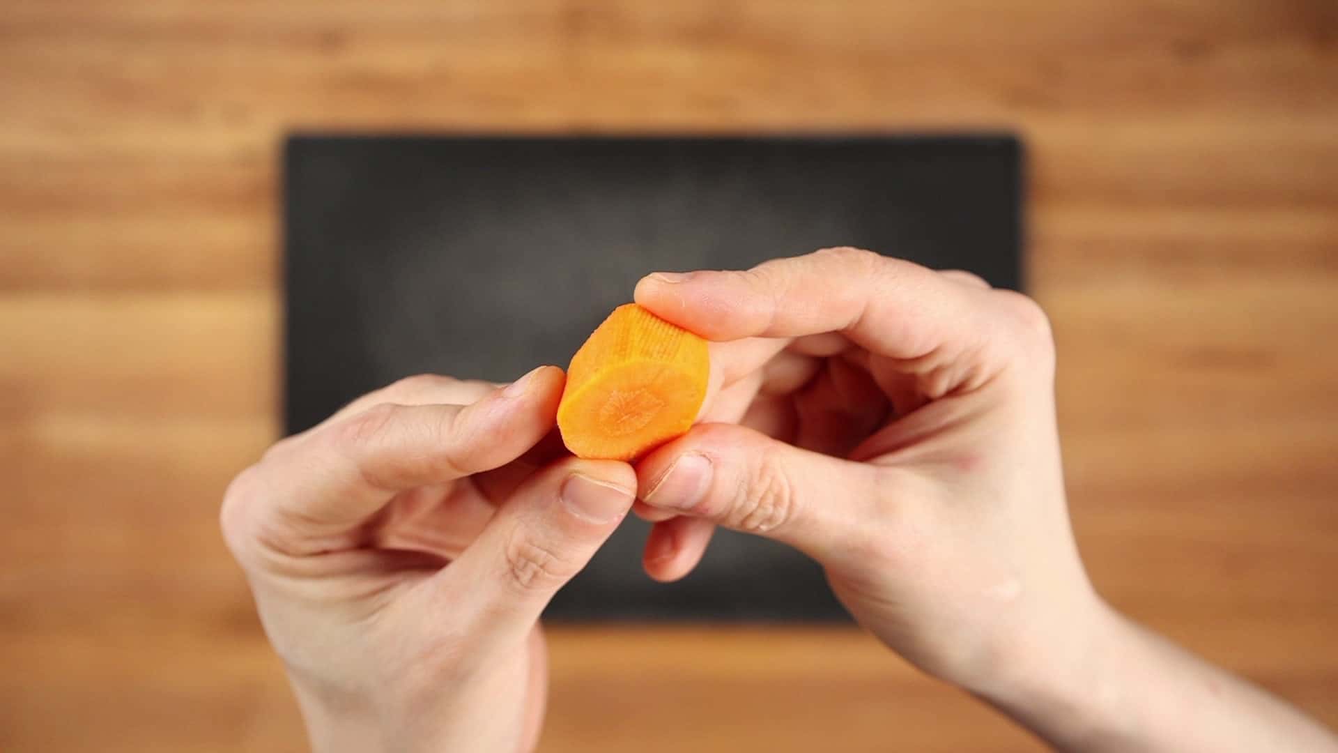 A carrot piece cut with a Japanese roll cut, showing its several flat sides