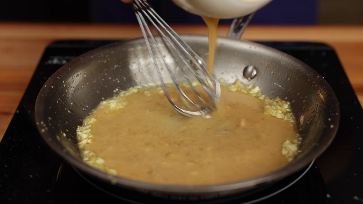 Pouring the miso mixture into the pan of garlic and ginger while whisking