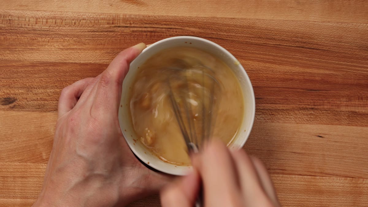 Whisking the miso paste, jam and water together in a small white bowl