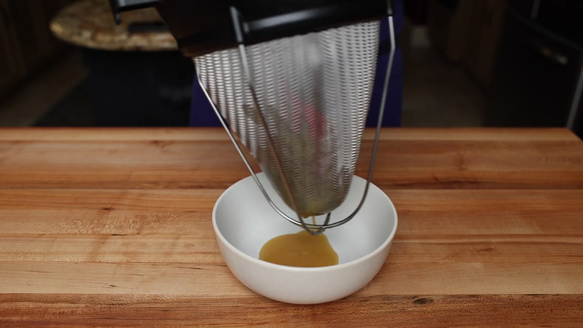 Miso sauce straining through a chinois into a small white bowl